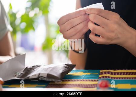 personne méconnaissable qui roule une cigarette à la maison Banque D'Images