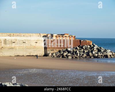 Les restes de fin de la jetée autrefois utilisée par l'acier travaille à marée basse avec un homme exerçant un chien d'Espagne Banque D'Images