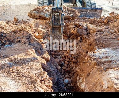Pelle hydraulique cassant et forant la route en béton pour la réparation de gros plan Banque D'Images
