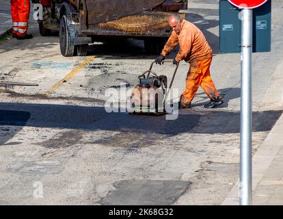 Frais de mise à niveau du travailleur au cours d'asphalte asphalte réparer ou de travaux de construction Banque D'Images