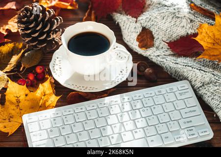 Clavier blanc pour ordinateur, feuilles d'automne colorées, tasse à café, pull chaud, concept, Style de vie, travail, détente Banque D'Images