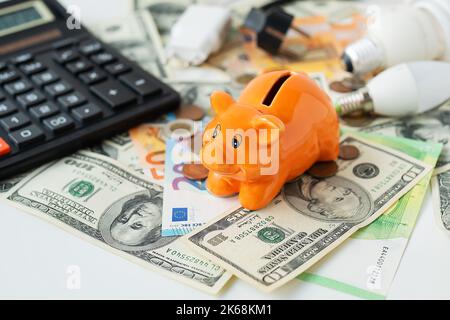 Tirelire de couleur orange sur le curry. Calculatrice, billets en euros et en dollars, pièces. Temps de taxe, paiement de facture, calculatrice de comptage. Banque D'Images