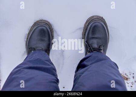 Les pieds des femmes dans des bottes noires qui serralisent la neige comme vu d'en haut. Vue de dessus, espace de copie, hiver Banque D'Images