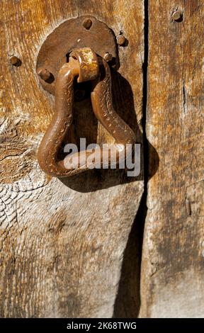 Poignée de porte en métal traditionnelle d'époque artisanale sur une porte en bois à l'entrée d'une maison en pierre espagnole, montagnes des Pyrénées, Espagne Banque D'Images