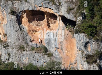 Deux personnes explorant les affleurements rocheux et les grottes qui abritent des vautours Griffon espagnols, des griffons d'Eurasion (Gyps fulvus) sous le soleil d'été Banque D'Images