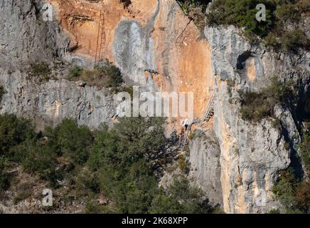 Deux personnes explorant les affleurements rocheux et les grottes qui abritent des vautours Griffon espagnols, des griffons d'Eurasion (Gyps fulvus) sous le soleil d'été Banque D'Images