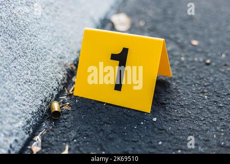 Un marqueur jaune de preuve de scène de crime dans la rue après un pistolet de tir à balles en laiton boîtier de balle 9mm pistolet de poing Banque D'Images