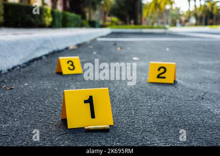 Un groupe de marqueurs jaunes de preuves de scène de crime dans la rue après un fusil à douille de balle en laiton tiré Banque D'Images
