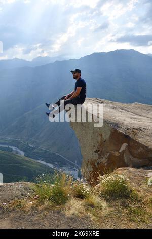 Dagestan, Russie - 21 juillet, 2022 : bon touriste au bord de la falaise au-dessus des abysses profondes. Crêtes de rochers près du village de Goor Banque D'Images