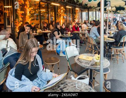 Personnes assises à l'extérieur dans un café à Paris, France Banque D'Images