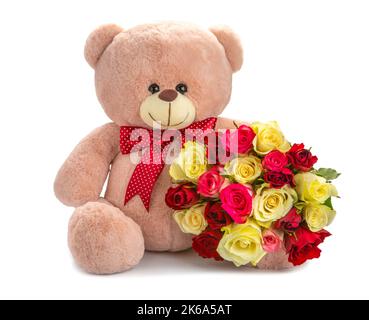 ours en peluche rose avec un noeud rouge et un bouquet de belles roses. concept cadeau sur fond blanc Banque D'Images