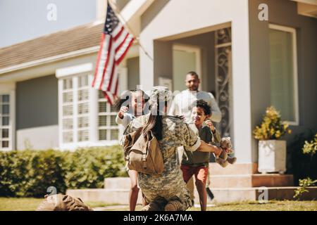 Servicewoman embrassant ses enfants après son arrivée à la maison de l'armée. Un soldat américain reçoit un accueil chaleureux de son mari et de ses enfants. Militaire W Banque D'Images