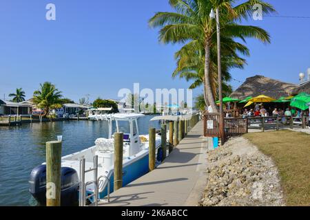 Vue sur les canaux avec des bateaux amarrés, à côté du restaurant et bar Phuzzy's Boat Shack avec toits de chaume et dîner en plein air à St. James City, Floride Banque D'Images