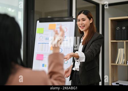 Une femme d'affaires ou un chef d'équipe asiatique du millénaire, attirante et professionnelle, dirige la réunion, discute et partage des idées avec son équipe. Banque D'Images