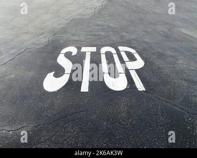 un panneau d'arrêt en asphalte sur route pavée peint symbole d'avertissement d'intersection de chaussée signalisation routière en toile de fond industrielle Banque D'Images