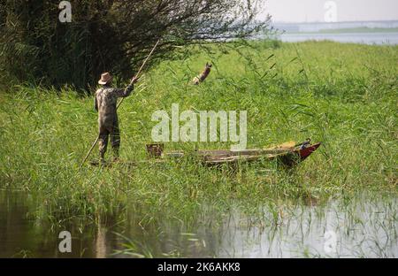 Pêcheur bédouin égyptien traditionnel en train de punter en bateau à ramer sur le Nil pêche par le bord de la rivière Banque D'Images