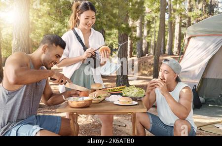 Être dans la nature nous rend affamés. Un groupe varié d'amis appréciant un repas ensemble pendant une journée dans les bois. Banque D'Images
