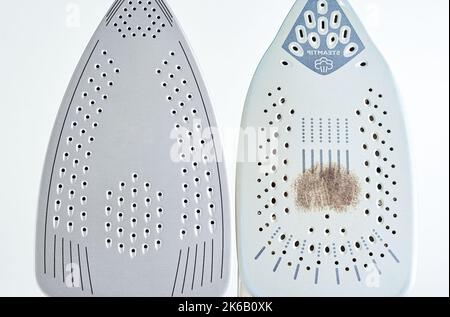 Fer ancien avec semelle endommagée et nouveau fer moderne sur fond blanc, entretien et entretien des appareils ménagers modernes Banque D'Images