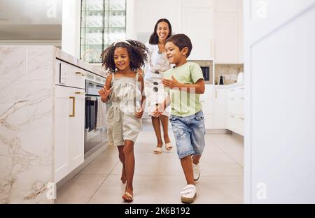 La mère, les enfants jouent ensemble le jeu de course à pied et le collage familial dans la cuisine à la maison. Une mère souriante et ludique, des enfants dynamiques heureux et enthousiastes Banque D'Images