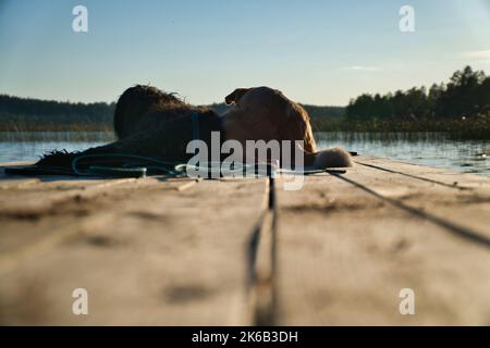 Amoureux des chiens allongé sur une jetée et regardant le lac en Suède. Goldendoodle et race mixte. Amitié animale. Photo d'animal avec charme. Banque D'Images