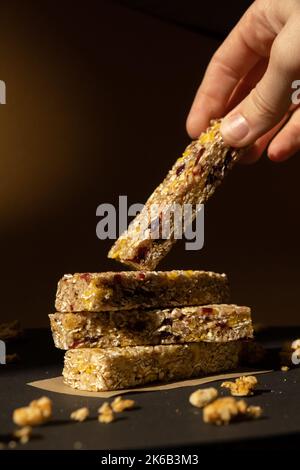 Femme prend le bar énergétique Granola naturel maison. Variété de barres de petit-déjeuner de granola de protéines, avec noix, raisins secs, cerises séchées et chocolat. Nutrition saine alimentation. Collation sans gluten aux céréales Super food Sport Oridge bar Vega dessert concept Banque D'Images