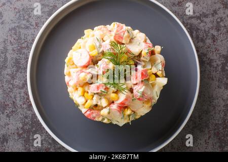 Salade épicée avec viande de crabe, maïs doux, oignon rouge, œufs durs et aneth dans l'assiette sur la table. Vue horizontale du dessus Banque D'Images