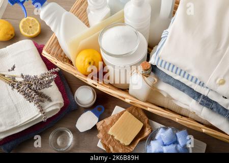 Groupe de produits chimiques et de lessive de remplacement sur une table avec des vêtements lavés et un fond de fenêtre. Vue de dessus. Composition horizontale. Banque D'Images