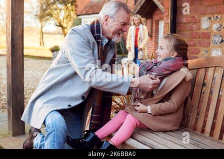 Grands-parents avec petite-fille à l'extérieur de la maison se préparer à partir pour la marche d'hiver Banque D'Images
