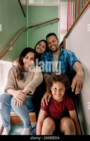 Portrait d'une famille heureuse assise ensemble sur les marches à la maison Banque D'Images