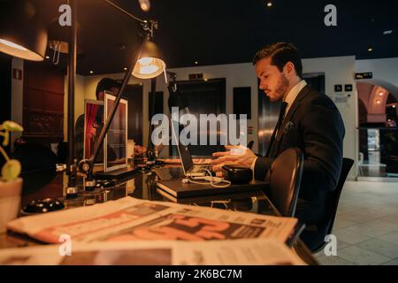 Jeune homme d'affaires avec ordinateur portable assis au bureau Banque D'Images