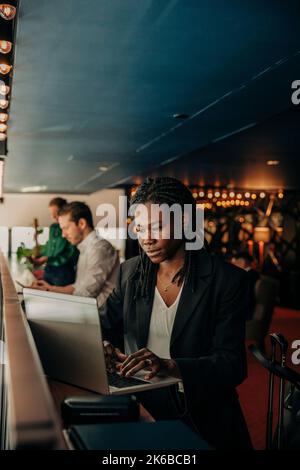 Jeune femme d'affaires qui tape sur un ordinateur portable lorsqu'elle est assise à l'hôtel Banque D'Images