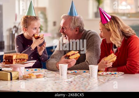 Grand-parents et petite-fille célébrant ensemble le gâteau d'anniversaire à la maison Banque D'Images