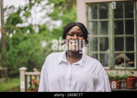 Portrait d'une femme mûre souriante debout dans l'arrière-cour Banque D'Images
