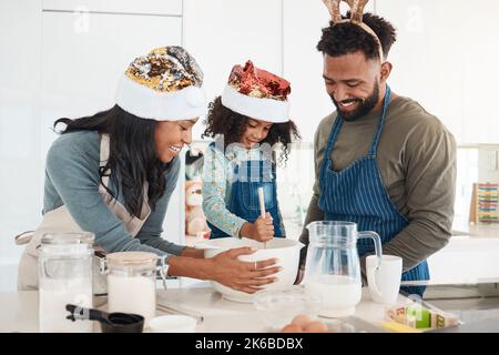 Mélange de la pâte. Un jeune couple affectueux et leur fille cuisent dans la cuisine à la maison. Banque D'Images