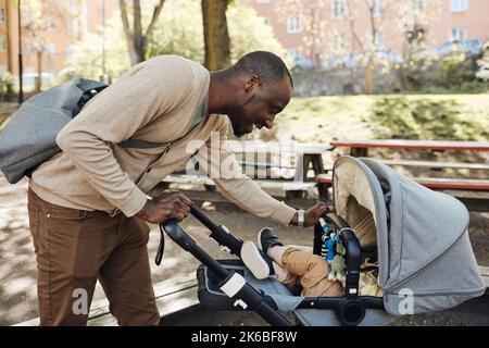 Père souriant regardant son fils dans la poussette de bébé Banque D'Images