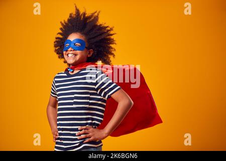 Studio Portrait de garçon habillé comme Comic Book Superhero contre fond jaune Banque D'Images