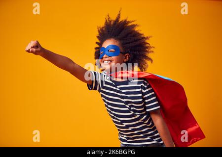 Studio Portrait de garçon habillé comme Comic Book Superhero contre fond jaune Banque D'Images