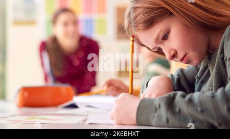 Une étudiante féminine avec des enseignants en classe écrivant dans le livre pendant la leçon Banque D'Images