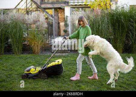 Femme joue avec son chien à l'arrière-cour tout en jardinant Banque D'Images
