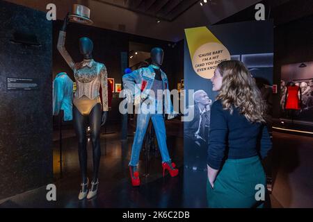 Londres, Royaume-Uni. 13 octobre 2022. Un membre du personnel avec (L) 'Costume pour Cassie dans Une ligne Chorus', 1976, et 'Costume pour Jamie New dans Everybody's Talking about Jamie', 2017-20, à un aperçu de 'Re:Imagining Musicals', une nouvelle exposition au V&A de South Kensington célébrant le monde du théâtre musical et son importance culturelle. L'exposition publique se déroule du 15 octobre au 27 novembre 2023. Credit: Stephen Chung / Alamy Live News Banque D'Images