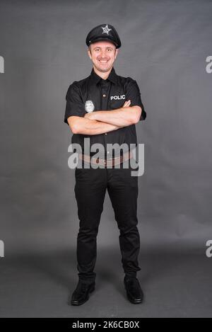 Portrait d'un homme de race blanche portant un costume de police sur fond gris de studio Banque D'Images