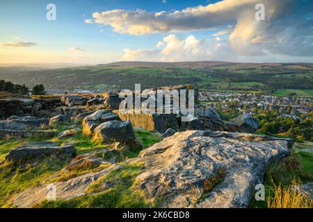 The Cow & Calf Rocks (vue pittoresque sur le village de la vallée de Wharfe, crag de haut douves, ciel bleu) - Ilkley Moor, West Yorkshire, Angleterre. Banque D'Images