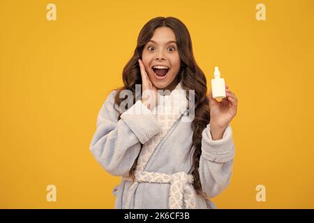 Une jeune fille surprise. Fille tenir médicament spray nasal de nez courant, pandémie de virus. Jeune fille malade avec vaporisateur nasal sur fond jaune. Excitée Banque D'Images