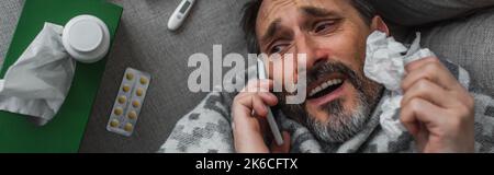 vue de dessus d'un malade tenant une serviette en papier et parlant sur un smartphone près de pilules et de contenants avec traitement, bannière, image de stock Banque D'Images