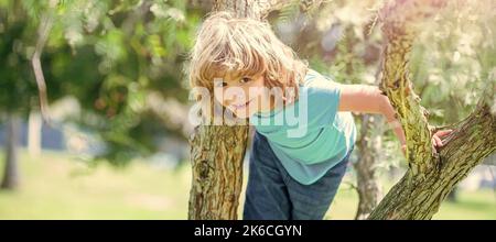 Grimper les arbres est toujours amusant. Arbre de montée enfant de garçon actif. Amusement d'enfance. En été. Affiche horizontale. En-tête de bannière Web, espace de copie. Banque D'Images