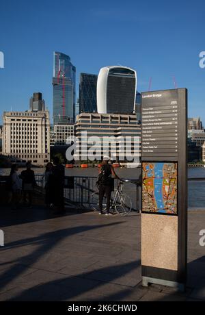 Vue depuis le sentier de la Tamise près du London Bridge jusqu'au Square Mile et au quartier financier de Londres, avec vue sur les gratte-ciels et le panneau de direction de la carte. Banque D'Images