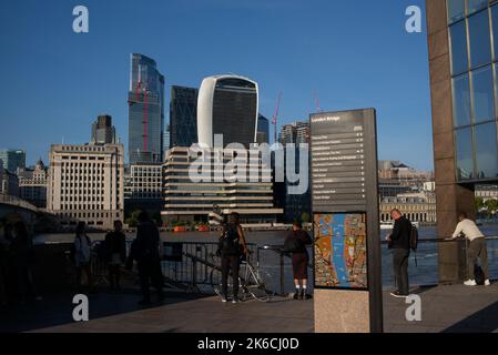 Vue depuis le sentier de la Tamise près du London Bridge jusqu'au Square Mile et au quartier financier de Londres, avec vue sur les gratte-ciels et le panneau de direction de la carte. Banque D'Images