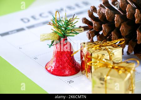 25th décembre jour de Noël sur Calendrier entouré d'un décor festif, un cône de pin, une cloche rouge brillant, et deux cadeaux enveloppés d'or, concept de Noël Banque D'Images