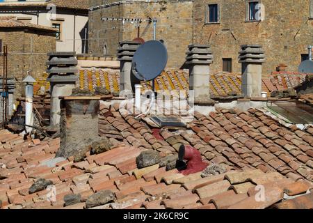 Situation chaotique sur les toits: Vue sur les tuiles, cheminées et antennes sur les toits d'un vieux village de Toscane, Italie Banque D'Images