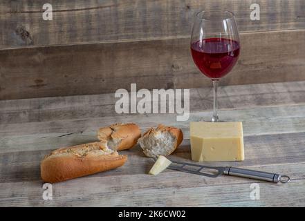 Fromage à pain et vin rouge sur un comptoir en bois. Banque D'Images